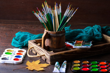 Paints for drawing and brush on a background in a composition