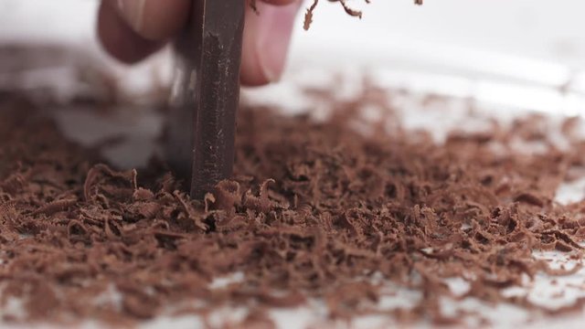 Closeup slow motion of making dark chocolate shavings with knife