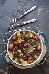 Bowl with Dublin coddle or Irish stew of sausages, bacon, onions and potatoes, top view on a brown stone background