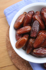 Bowl of dried dates on wooden background

