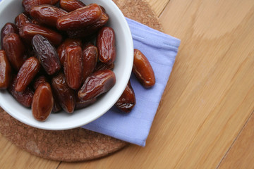 Bowl of dried dates on wooden background
