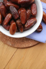 Bowl of dried dates on wooden background
