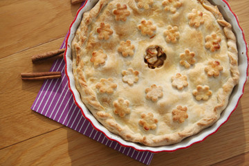  homemade apple pie with cinnammon and cookies on wooden table
