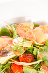 Baby spinach, dry sausage, matured cheese, roast tomatoes, thyme-balsamic vinaigrette salad on a white background