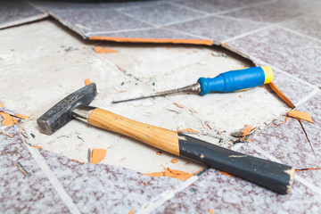 Hammer and chisel lay on floor without tiles