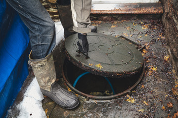 hand opens sewer hatch in yard
