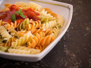 colored pasta with tomato sauce on plate close up