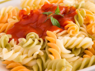 colored pasta with tomato sauce on plate close up