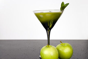 Green fruits and vegetables juiced in cocktail glass with a sprig of mint