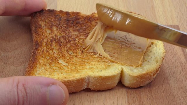 Spreading creamy peanut butter on toast