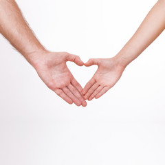 Young couple close to each other and smiling making heart shape made with their fingers isolated on white background.