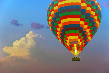 Colorful hot air balloon is flying at rose sundown sky of the cloud