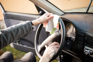 Young man hands cleaning dirty car full of dust by rag (color toned image)