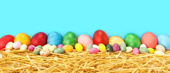 Row of  Easter eggs  assorted colorful collection on rustic straw with cyan blue background 