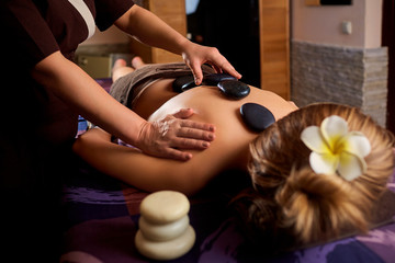 Stone massage back spa for a woman in the beauty center.