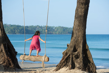 ビーチのブランコで遊ぶ女の子