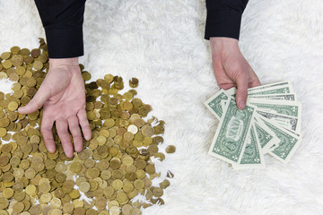 The choice between paper and metal money. A man in one hand holds a bundle of paper dollars, and...