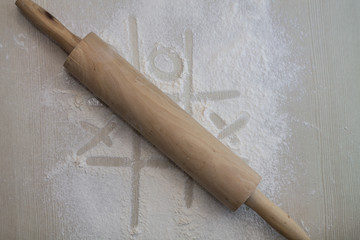 rolling pin  laying on the flour with tic-tac-toe drawing 