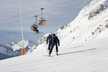 Fototapeta na wymiar Two policemen on skis. Police in a ski resort. Rescuers in the mountains. the policeman descends on skis. Valbona, Lusia, Bellamonte.