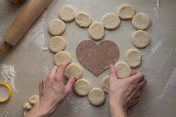man's hands making a heart using unbaked cookies for St. Valentine's Day