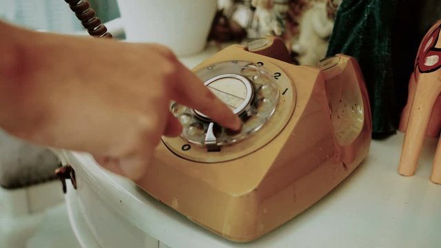 4K. people use finger dialing an retro rotary vintage style telephone. film dye for vintage tone. old telecommunication technology
