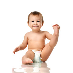 Beautiful infant baby girl toddler sitting in diaper and hold one leg 