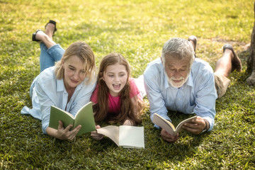 Family is reading happily together in the garden.Soft focus concept.
