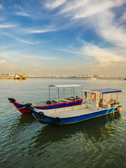 Speed boats at the Clan Jetties of Georgetown with a city view and a dramatic blue sky in the background - Penang, Malaysia