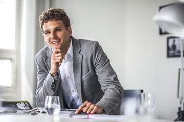 Portrait of confident young businessman working at office table