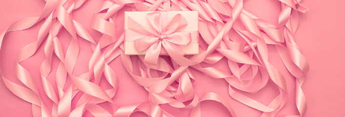 Banner Boxes with gifts on the background of a Coil of decorative satin ribbons of pink color.