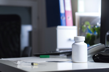 Malpractice, bad healthcare, negligence, medical fraud or abuse or treatment error concept. Medicine bottle on table and desk in doctor office in hospital. Dramatic lighting. Illegal or fake doctor