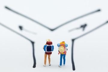 Miniature people : Backpacker walking follow arrow. Image use for travel, business concept.