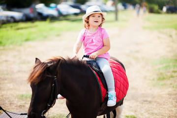 Cute toddler girl riding a horse.
