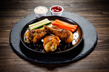 Roast chicken drumsticks on wooden background