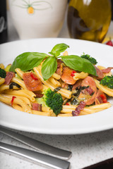 A delicious fresh gourmet Italian strozzapreti pasta dish, with pancetta, italian sausage, broccoli, vegetables, topped with fresh basil.