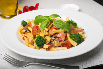 A delicious fresh gourmet Italian strozzapreti pasta dish, with pancetta, italian sausage, broccoli, vegetables, topped with fresh basil.