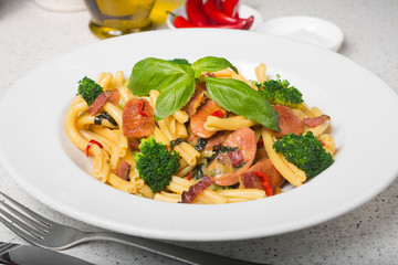 A delicious fresh gourmet Italian strozzapreti pasta dish, with pancetta, italian sausage, broccoli, vegetables, topped with fresh basil.