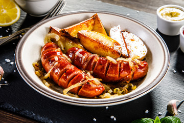 Grilled sausages and vegetables on wooden table