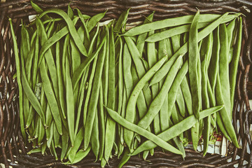 Organic natural imperfect vegetables with disabilities in a wicker basket on the market. Natural ecological green beans, legumes in the bazaar. Perfect background for a healthy organic food.