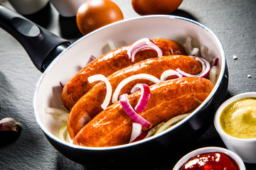 Sausages in pot on black stone