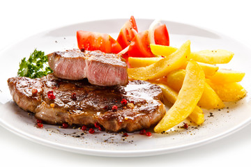 Grilled steaks, French fries and vegetables