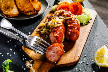 Grilled sausages with toasts on wooden table