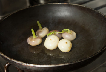Fresh organic baby turnips, in a metal frying pan, to be cooked and caramelised.