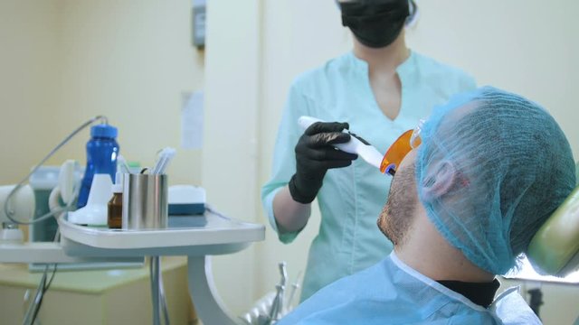 Doctor and patient in the dental office, polymerisation of fillings with a protective screen,
