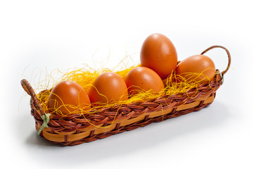 Eggs of brown chicken in a basket on a white background for Easter