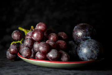 Grapes on a plate together with plums