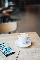 Coffee on the wooden table by the window light with Samsung galaxy note 8 on the table