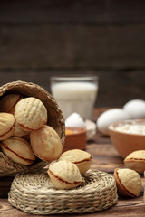 delicious walnut shaped shortbread sandwich cookies filled with sweet condensed milk and chopped nuts on old wooden background, view from above, close-up
