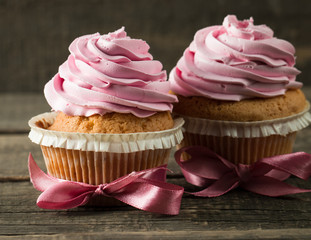 Closeup of cupcakes with vanilla, berries, pink and white cream, chocolate and sprinkles on wooden background. Selective focus. Sweet dessert tasty food concept muffin.