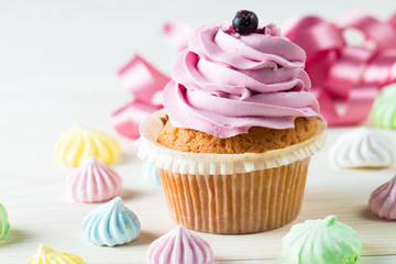 Closeup of cupcakes with vanilla, berries, pink and white cream, chocolate and sprinkles on wooden background. Selective focus. Sweet dessert tasty food concept muffin.